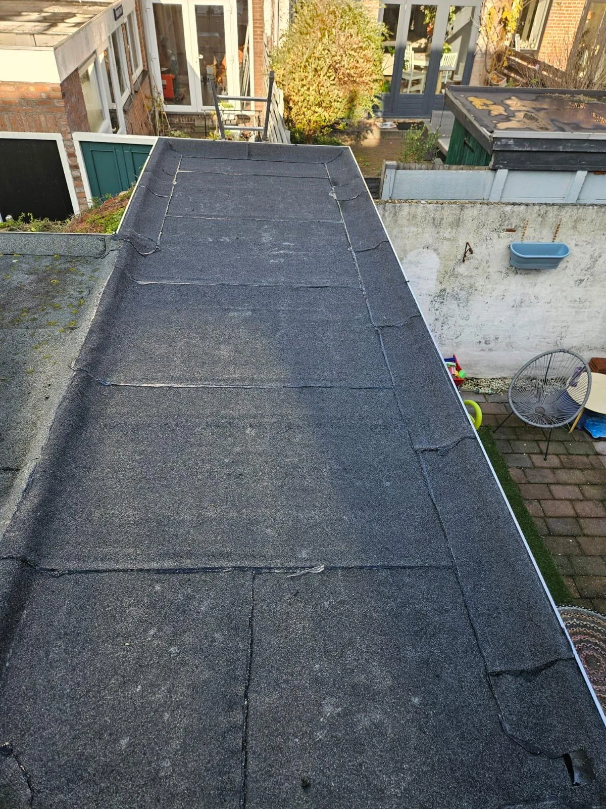 Plat dak met bitumen dakbedekking op een aanbouw in een woonwijk in Alkmaar